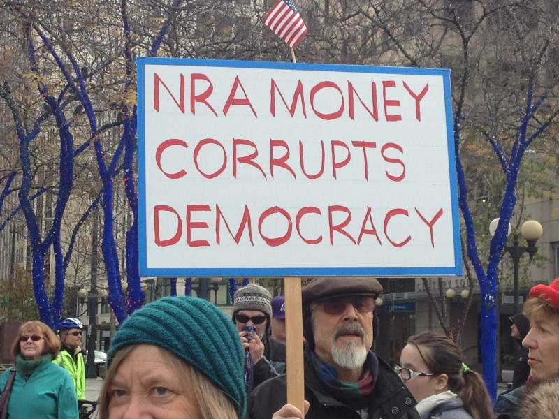 Sign at Seattle rally reads "NRA money corrupts democracy"