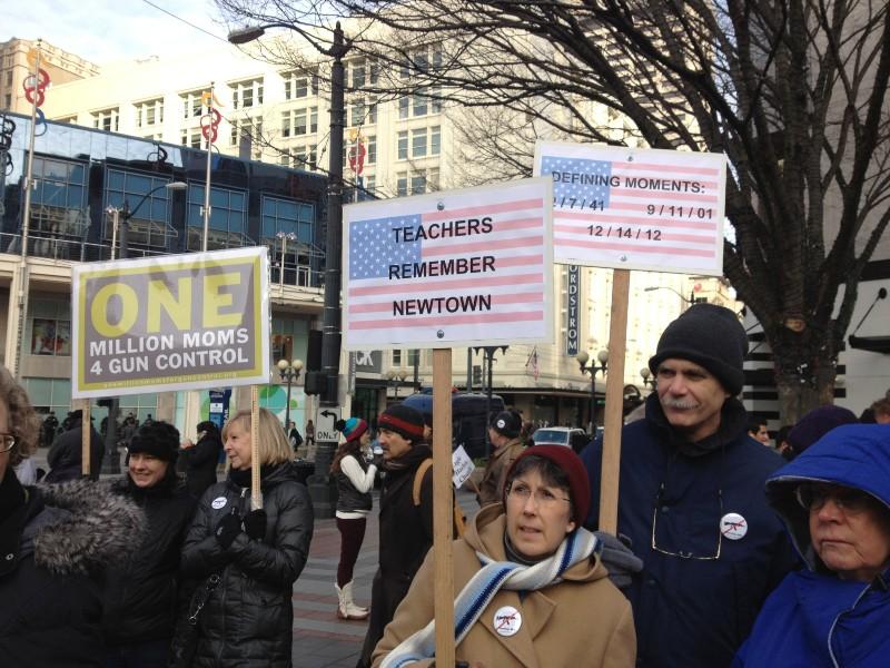 Signs at Seattle rally say "one million moms for gun control" and "teachers remember Newtown"